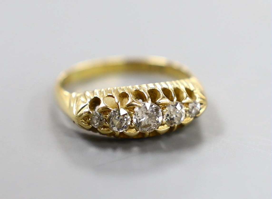 An Edwardian 18ct gold and graduated five stone diamond set half hoop ring, size P, gross weight 4.9 grams.